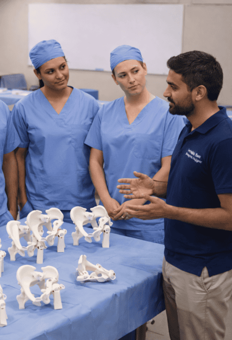 Medical team discussing surgical procedures with pelvic models on a table.